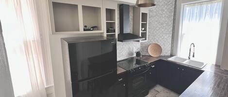 Een moderne keuken met een zwarte koelkast, inbouwmeubels, een houten aanrecht en een hangende pendelverlichting.