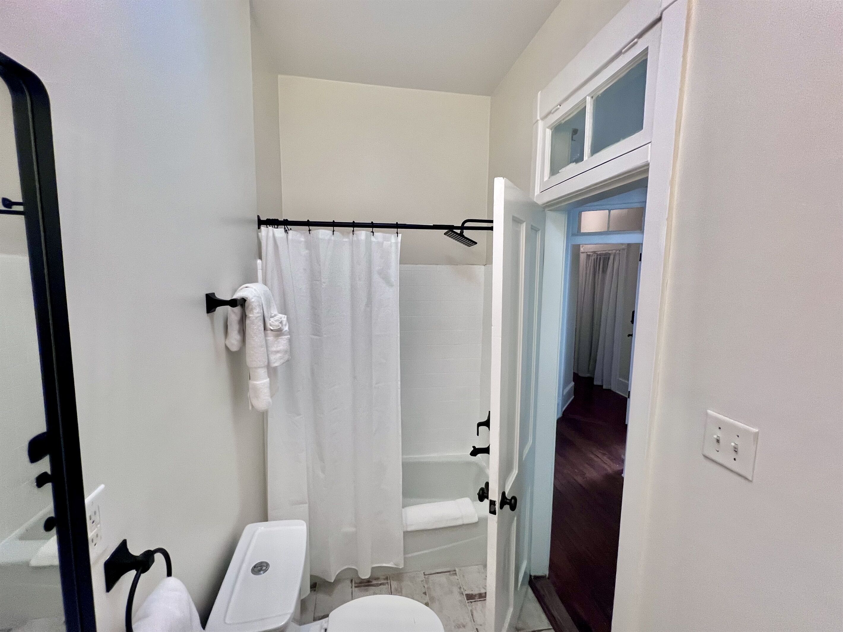 Une petite salle de bain avec des toilettes, un rideau de douche et une baignoire.