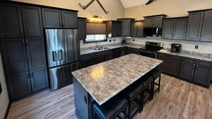 Una cucina moderna con mobili scuri, elettrodomestici in acciaio inossidabile e un piano di lavoro in granito.