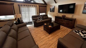 Un soggiorno spazioso con soffitto alto, ampie finestre e una televisione a schermo piatto.