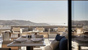 Un espacio de comedor al aire libre con mesas y sillas, vistas al paisaje y una estructura de techo de madera.