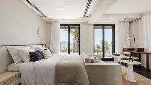 Un dormitorio moderno con una cama grande, un sofá, una mesita y vistas al exterior.