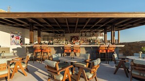Zona de bar al aire libre con mobiliario de madera y una variedad de botellas.