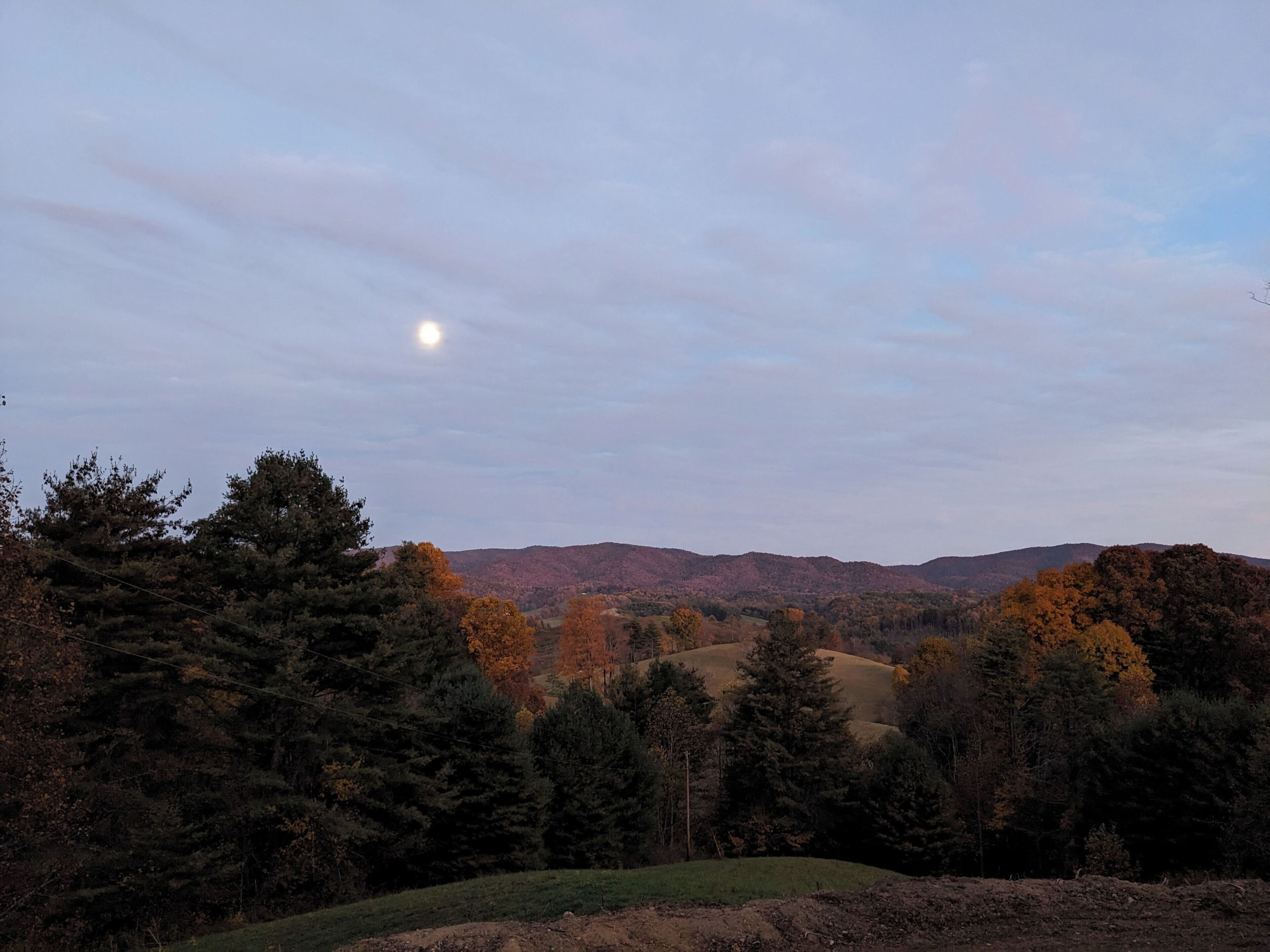 A landscape with a hill, trees, and a clear sky.