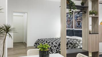 Ein modernes Schlafzimmer mit einem Bett, einem Schreibtisch mit zwei Tassen und einer Topfpflanze.
