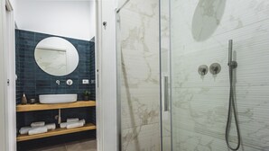 A modern bathroom with a round mirror, a sink, and a glass-enclosed shower.