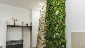 Ein modernes Zimmer mit einer Wand aus Naturstein, integrierten Regalen und einer Küchenzeile mit einem Weinglas.