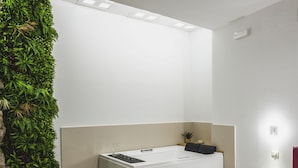 Ein modernes Schlafzimmer mit einer eingebauten Badewanne, einem Bett und einer grünen Wand mit Pflanzen.