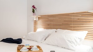 A neatly made bed with white linens, a wooden headboard, and a tray with cups and a basket on the bedside table. - 4bnb - Reale House Borgo (Rome)
