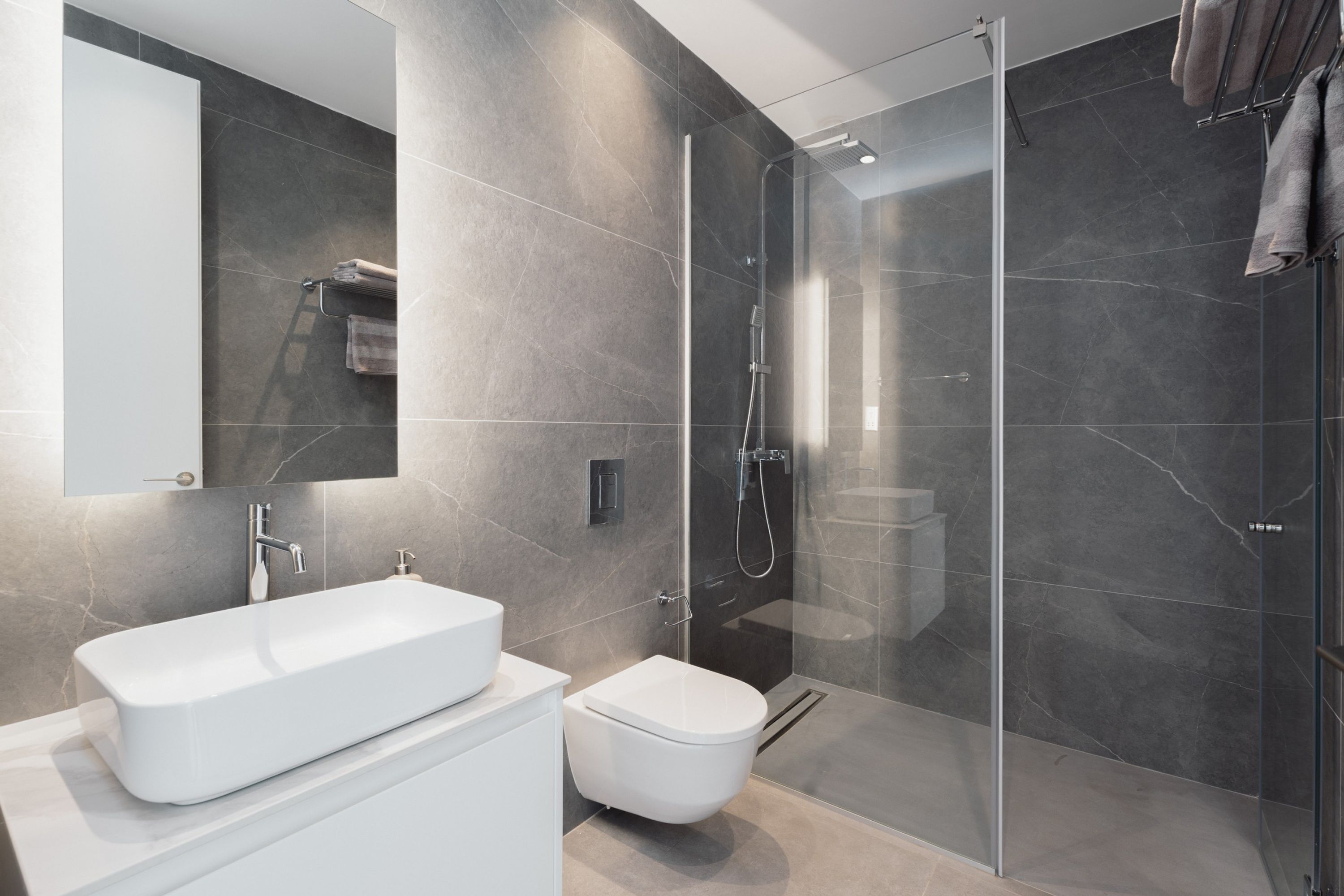 Ein modernes Badezimmer mit einem großen, weißen Waschbecken, einer Toilette und einer Duschkabine aus Glas.