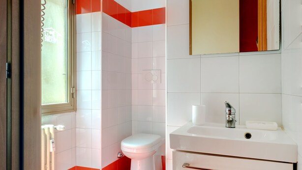 A bathroom with a toilet, sink, and a window.