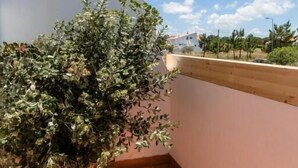 A balcony with a potted plant, a tiled floor, and a clear blue sky with clouds. - Utopia (Aljezur)