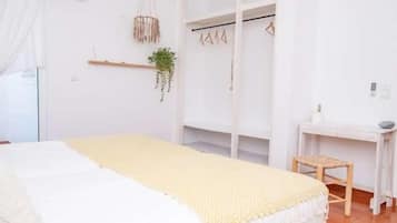 A bedroom with a bed, a desk, and a hanging plant.