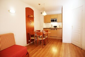Um espaço compacto com área de jantar, cozinha compacta e sofá vermelho.