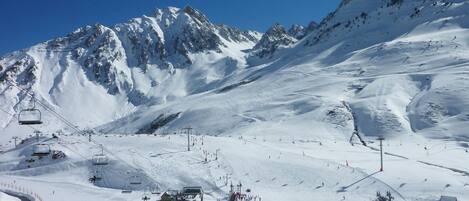 A snow-covered ski resort with ski lifts, a chairlift, and a mountain backdrop.