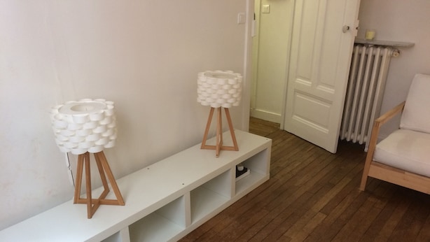 Un banc blanc avec des étagères, deux supports décoratifs blancs, un plancher en bois et une chaise blanche.