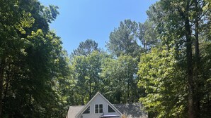 Ein Haus mit Veranda, umgeben von Bäumen und einem gepflasterten Weg dorthin.