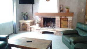 A living room with a brick fireplace, a television mounted on the wall, and a green sofa.