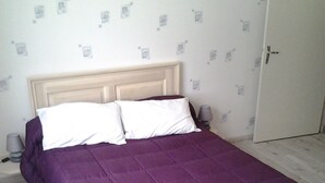 A bed with a headboard, two bedside lamps, and a door to the right.