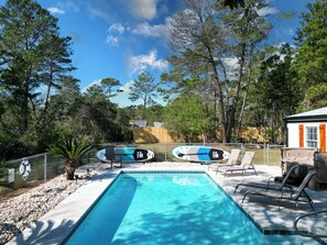A swimming pool with lounge chairs and two paddleboards. - Private Pool! Hot Tub! Golf Cart! Bikes! Walk to Beach! Paddle Boards! (Panama City Beach)