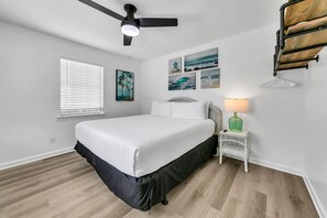 A bedroom with a bed, a ceiling fan, a window with blinds, and wall art. - Private Pool! Hot Tub! Golf Cart! Bikes! Walk to Beach! Paddle Boards! (Panama City Beach)