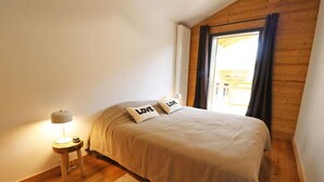 A bedroom with a bed, a bedside lamp, and a window with curtains.