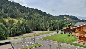 A hotel with a wooden exterior, a parking lot, and a view of a forested mountain.