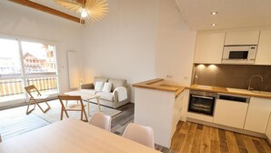 A modern apartment with a dining area, a kitchen with a microwave and oven, and a living room with a sofa and chairs. - 300m from ski slopes, 3rd floor, balcony, 50m², Les Gets (Les Gets)