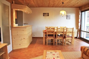 A dining area with a wooden table and chairs, a wooden cabinet, and a window with curtains.
