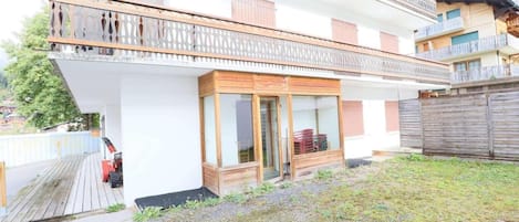 Ein zweistöckiges Gebäude mit Holzbalkon, Glastür und kleinem Garten.