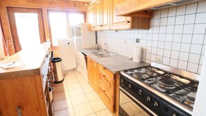 A kitchen with wooden cabinets, a stainless steel stove, a sink, and a dishwasher. - Ground floor, parking, tv, 97m², Les Gets (Les Gets)