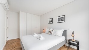 Et moderne soveværelse med en stor seng, et natbord med lampe og to billeder i rammer på væggen.