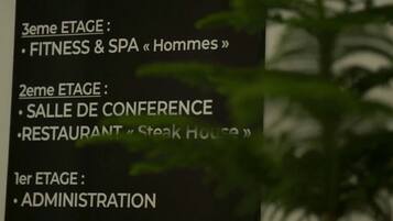 A sign listing the different stages of a hotel or conference center, including fitness and spa facilities, a conference hall, a restaurant, and administration.
