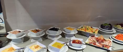 A buffet with various dishes including salads, fruits, and meats.