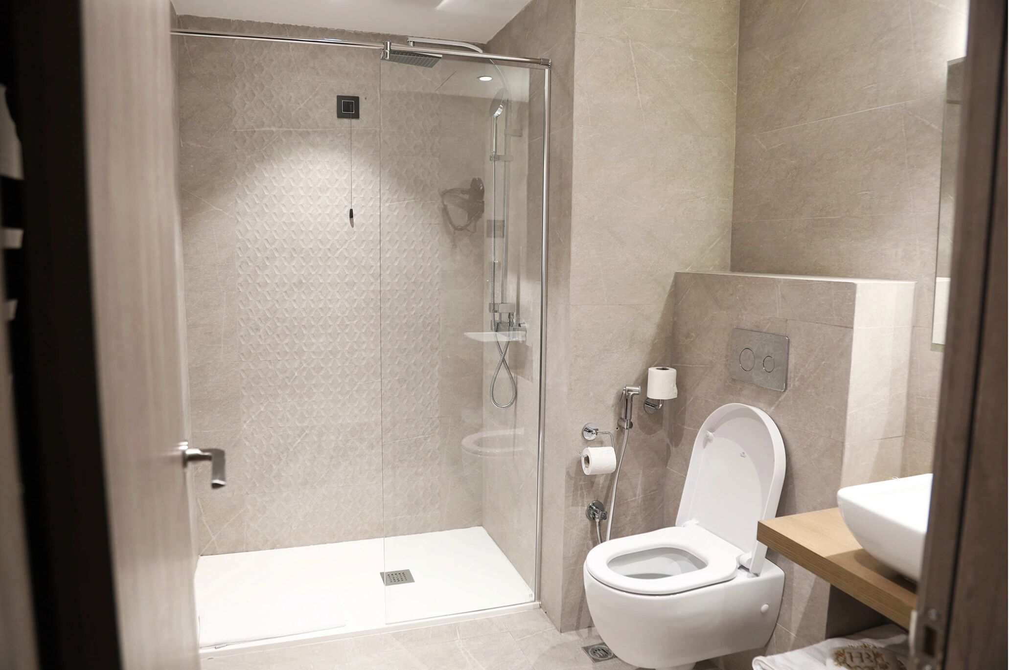 A modern bathroom with a glass-enclosed shower, a white toilet, and a sink.