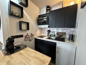 A compact kitchen with a microwave, oven, and a coffee maker on the counter.