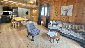 Un intérieur de chalet chaleureux avec un coin repas, un canapé et une cheminée.