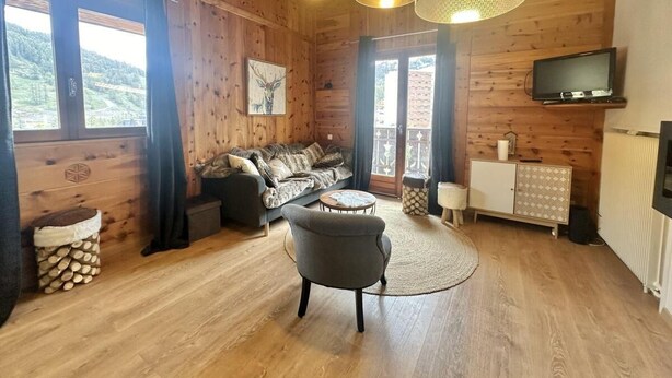 L’intérieur d’un chalet accueillant, avec un plancher en bois, un canapé, une petite table et un téléviseur.