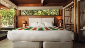 A large bed with a striped blanket, wooden headboard, and two bedside lamps. - Monte da Vilarinha (Aljezur)