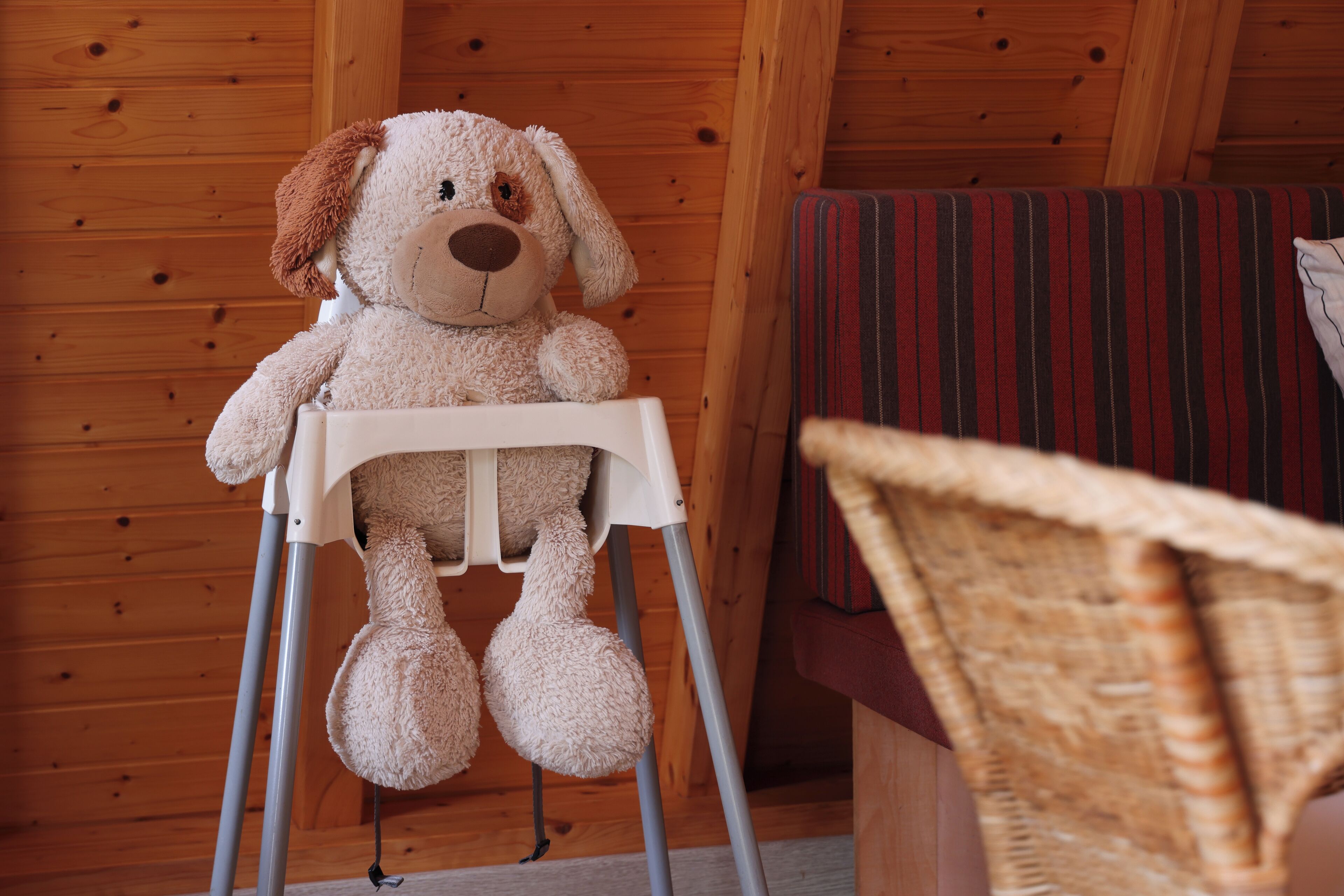 A wooden cabin interior with a high chair holding a plush dog toy.
