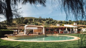A pool surrounded by a well-maintained lawn and a building with a tiled roof. - Monte da Vilarinha (Aljezur)