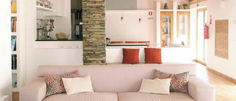 A modern living room with a wooden ceiling, a stone pillar, a sofa, and leather armchairs.