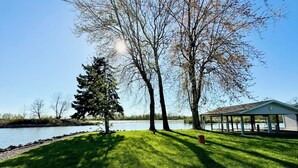A grassy area with a gazebo and a tree by a body of water. - Lake House Cottage w/ Breathtaking Views! (Lakeview)