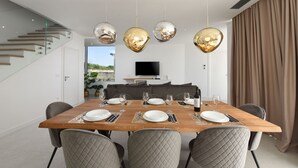 A modern dining area with a wooden table set for six, a staircase, and a TV in the background. - Villa Dante Zadarvillas (Sukosan)