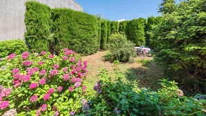 A garden with hedges, flowering plants, and a table with chairs. - Holiday apartment with air conditioning (Valbandon)