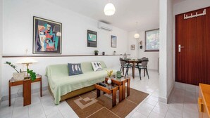 A living room with a sofa, coffee table, and a dining area with chairs and a table. - Holiday apartment with air conditioning (Valbandon)