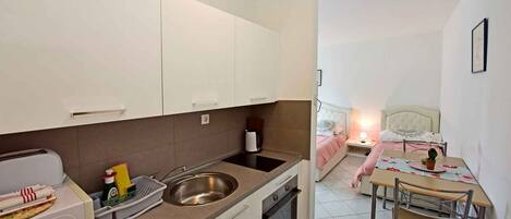 A compact kitchen with a sink, stove, and a dining area with a table and chairs.