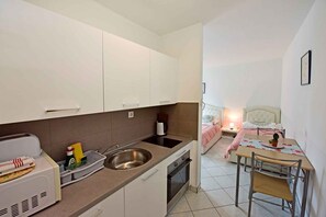Cozinha compacta com pia, fogão e área de refeições com mesa e cadeiras.