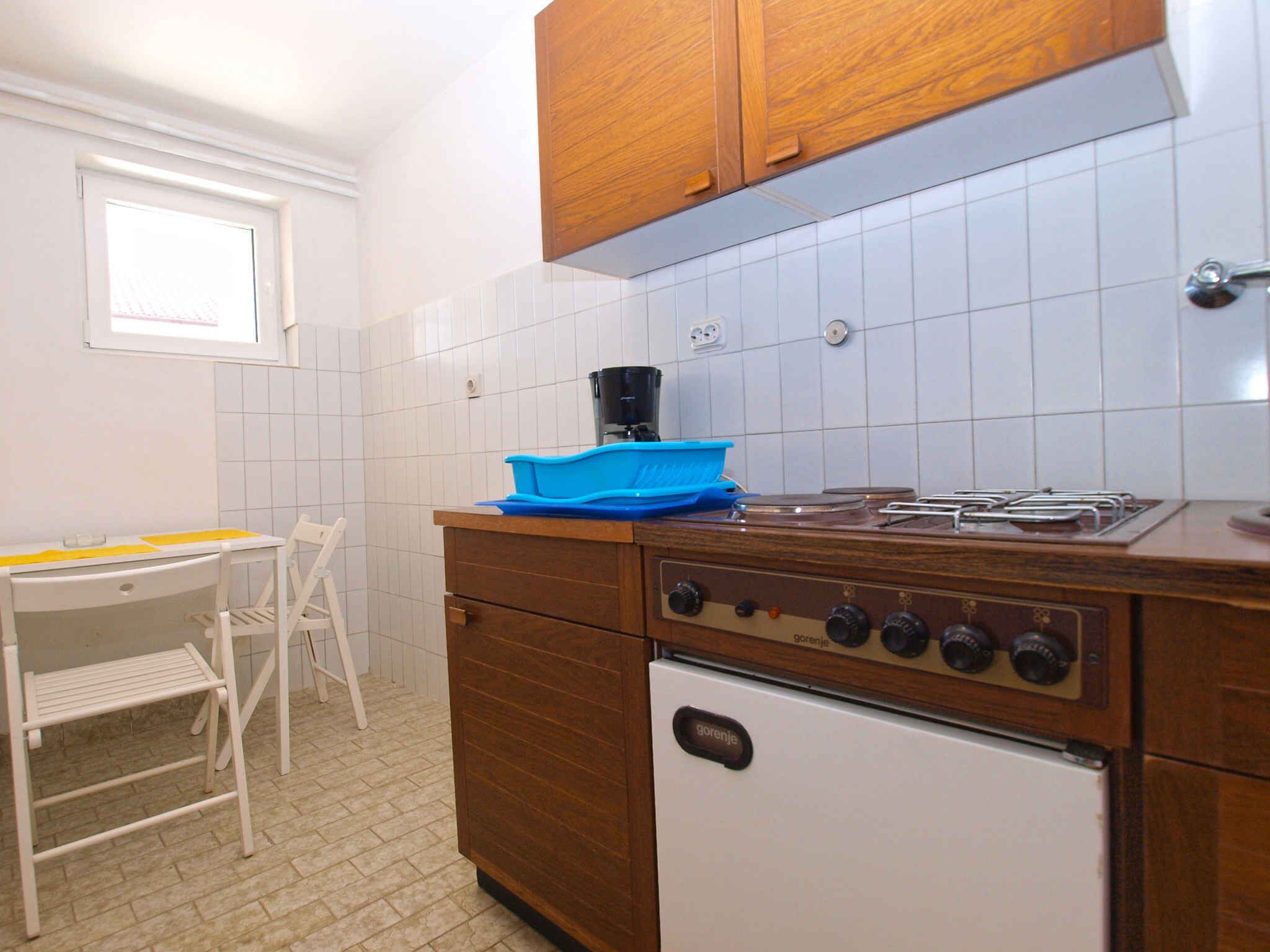 Una cocina compacta con estufa a gas, un refrigerador blanco y un armario de madera.