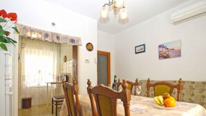 A dining area with a table set for two, wooden chairs, a chandelier, and a dining table with a floral tablecloth. - Holiday apartment with terrace (Štinjan)
